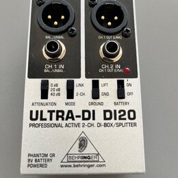 Stříbrná DI-box s černým horním panelem. Na zařízení jsou nápisy ULTRA-DI DI20, PROFESSIONAL ACTIVE 2-CH. DI-BOX/SPLITTER a logo BEHRINGER s webovou…
