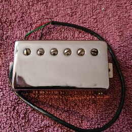 Stříbrný humbucker s chromovaným krytem a šesti viditelnými šrouby. Z nástroje vedou červený, zelený a černý vodič. Povrch krytu vykazuje drobné škrá…