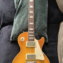 Elektrická kytara s žlutým gradientním lakem a bílým plechtrzem. Na hlavě hředu je viditelné logo Gibson. Nástroj má dva humbuckery, čtyři ovládací k…