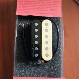 V plastovém obalu na černém molitanu jsou dva kytarové snímače typu humbucker, jeden v černé a druhý v krémové barvě. Na černém snímači je svisle nap…