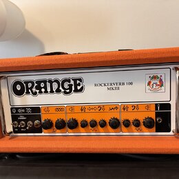 Kytarový zesilovač v oranžovém texturovaném potahu s bílým předním panelem. Na panelu je velký nápis ORANGE a modelové označení ROCKERVERB 100 MKIII…