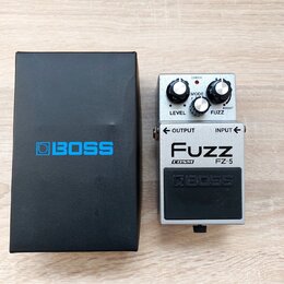 Stříbrný efekt pedál s černým ovládacím spínačem a dvěma černými otočnými knoflíky. Na pedálu jsou nápisy LEVEL, MODE, FUZZ, OUTPUT, INPUT a logo BOS…