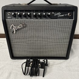 Černý kytarový kombozesilovač s šedou textilní maskou reproduktoru. Na horním ovládacím panelu je nápis Super Champ x2 a VINTAGE MODIFIED TUBE AMPLIF…