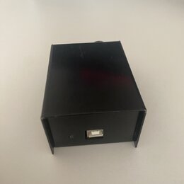 Černý obdélníkový box z kovového nebo plastového materiálu. Na přední straně je umístěn jeden USB port a malá čtvercová kontrolka. Povrch je hladký a…