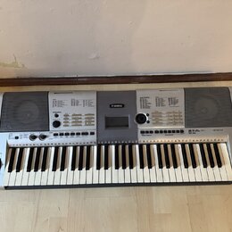 Stříbrošedý digitální klavír s bílými a černými klávesami. Na horním panelu je uprostřed logo YAMAHA a vpravo nápis PSR-E403. Nástroj obsahuje disple…