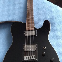 Černá elektrická kytara s tmavým hmatníkem a světlou hlavou. Na hlavě je viditelné logo "Squier". Kytara má dva snímače, přičemž na spodním je nápis…
