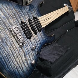 Elektrická kytara s modrým plamenovitým povrchem těla a světlým hnedým hmatníkem. Nástroj má tři humbuckery, chromovaný most a dva ovládací knoflíky.…
