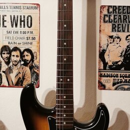 Elektrická kytara s trupem v barevnosti sunburst a černým pickguardem. Na hlavě hmatníku je nápis "Squier STRAT". Nástroj má hmatník z tmavého dřeva…