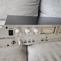 Stříbrný dvoukanálový mikrofonní předzesilovač s nápisem MPA GOLD. Přední panel obsahuje přepínač POWER, knoflíky INPUT GAIN a INPUT IMPEDANCE (označ…