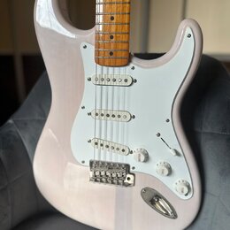 Elektrická kytara s bílým tělem a hnědým dřevěným hmatníkem. Nástroj má bílý pickguard, tři snímače a tři ovládací knoflíky s nápisy VOLUME, TONE a T…