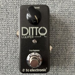 Černý kytarový pedál s nápisy DITTO a LOOPER. V horní části je ovládací knoflík s popiskem level, ve spodní části stoupací spínač s nápisem true bypa…