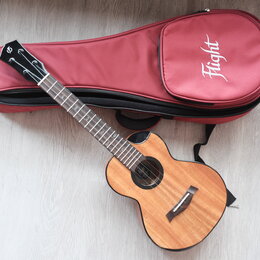Dřevěný akustický nástroj typu ukulele v přirozené barvě s černým lemováním. Na hlavě hmatníku je bílé logo znázorňující stylizované písmeno S. Vedle…