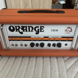Kytarový kombozesilovač v oranžovém texturovaném potahu s černou rukojetí. Na bílém předním panelu je velký nápis ORANGE a označení modelu TH30. Pane…