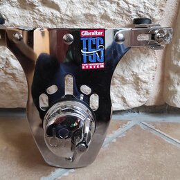 Chromovaný kovový držák na činely. Na horní části je nalepený štít s nápisy Gibraltar, TSS a TOM SUSPENSION SYSTEM. Povrch je lesklý s viditelnými od…