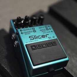 Modrý kytarový efekt pedál s černým nášlapným spínáčem. Na horní straně je bílý nápis Slicer SL-2 a pod ním text SET TEMPO/HOLD. Na spínáči je vyraže…