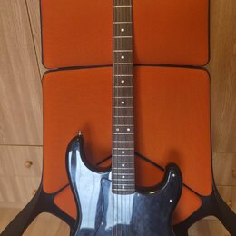 Černá elektrická kytara s tmelem v barvě přírodního dřeva. Na hlavě je viditelné logo Squier. Kytara má tři snímače, chromovaný most a ovládací knofl…