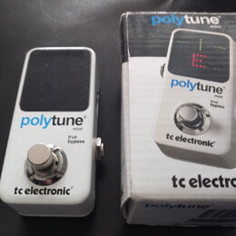 Bílý kytarový ladič s černým displejem a kovovým spínacím tlačítkem. Na přístroji jsou nápisy polytune mini, true bypass a tc electronic. Vedle ladič…