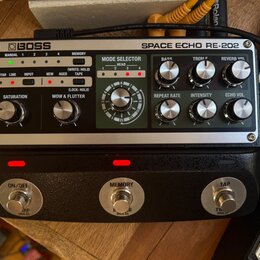 Stříbrný efektový pedál s černým spodním tělem a nápisy BOSS SPACE ECHO RE-202. Horní panel obsahuje ovládací knoflíky, přepínače a sekci MODE SELECT…