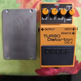 Kytarový efekt pedál oranžové barvy s černým spínacím tlačítkem. Na přední straně je nápis TURBO Distortion DS-2 a logo BOSS. V horní části jsou čtyř…
