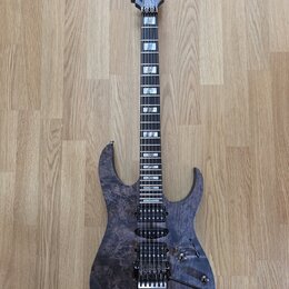 Elektrická kytara s tmavě fialovým průsvitným povrchem s viditnou strukturou dřeva. Na hlavě hmatníku je bílý nápis Ibanez. Nástroj má dva humbuckery…