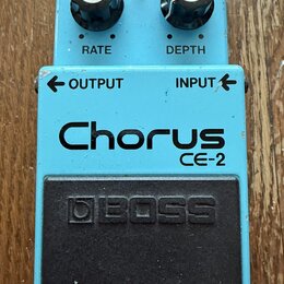 Modrý efekt pedál s nápisy Chorus a CE-2. Na horní části jsou dva černé ovratovky s popisky RATE a DEPTH, červená kontrolka CHECK a vstupy OUTPUT a I…