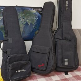 Tři černé softcasy na kytary z textilního materiálu. Nejlevý obal má bílý nápis LINE, prostřední červený nápis Fender a pravý bílý svislý nápis RITTE…