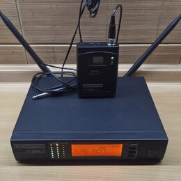 Černý bezdrátový přijímač s dvěma anténami a nápisem LD SYSTEMS WS1000/QR. Na přední straně je oranžový displej s hodnotou 826.300 MHz a řada kontrol…