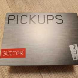 Stříbrná krabice s texturou broušeného kovu. V horní části je velký černý nápis PICKUPS a v pravém dolním rohu logo EMG. V levém dolním rohu je červe…