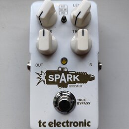 Bílý kytarový efekt s čtyřmi bílými oválnými knoflíky. Na pedálu jsou nápisy FAT CLEAN MID, LEVEL, TREBLE a logo SPARK BOOSTER s motivem zapálené záp…