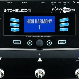 Černý procesor efektů s modrým displejem, na kterém je nápis HIGH HARMONY 1. Na horní části jsou loga TC-HELICON a play ACOUSTIC. Zařízení obsahuje n…