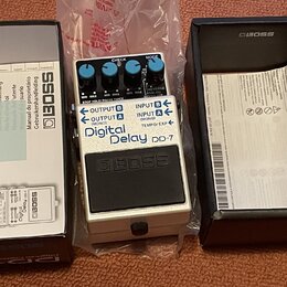 Bílá efekt pedál s černým spínacím tlačítkem a třemi ovládacími knoflíky. Na pedálu je nápis Digital Delay DD-7 a logo BOSS. Součástí je originální k…