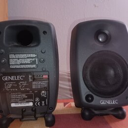 Dva šedé studiové monitory značky GENELEC. Na zadní straně levého reproduktoru je vidět nápis „GENELEC“, modelové označení „8020B BI-AMPLIFIED MONITO…