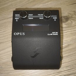 Černý kytarový efekt s nápisy OPUS a AMP SIM DynIR ENGINE. Zařízení má dva ovládací knoflíky a tlačítka s popisky PERFOR., PRESET, VOLUME, MENU, PARA…