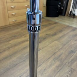 Detail chromovaného kovového stojanu. Na středové části je černý nápis 1000 HARDWARE SERIES. Povrch je lesklý, s viditelnými odrazy okolí.