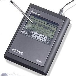 Tmavě šedý digitální přístroj s displejem a ovládacími tlačítky. Na horní části je bílý nápis Roland, v dolní části nápis PMA-5 PERSONAL MUSIC ASSIST…
