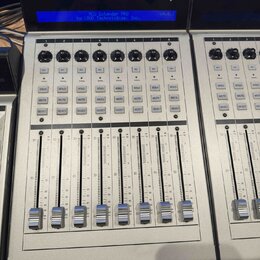 Šedý kontrolní panel NCU Extender PRO by LOUD Technologies, Inc. s modrým displejem, na kterém je stejný nápis a verze 04.0.3. Zařízení obsahuje osm…