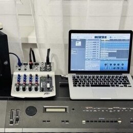 Sestava hudebního vybavení na šedém podkladu. V popředí je digitální piano s nápisem ROLAND DIGITAL PIANO RD-1000. Nad ním jsou dva černé studiové mo…