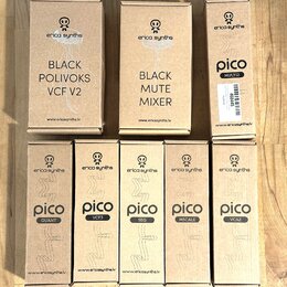 Fotografie zobrazuje osm kartonových krabic od modulárních syntetizátorů značky erica synths. Horní řada obsahuje krabice s nápisy BLACK POLIVOKS VCF…