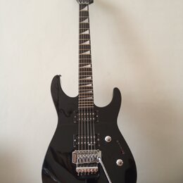 Černá elektrická kytara s dvojstupňovitým úhlem hlavy a hrotovými polohovými značkami na hmatníku. Na těle jsou dva humbuckery, ovládací knoflíky a t…