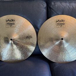 Dvě mosazné činely s viditelným broušením povrchu. Oba mají v horní části logo paiste Twenty a nápis TRADE MARK MADE IN SWITZERLAND. Levý činel má vp…