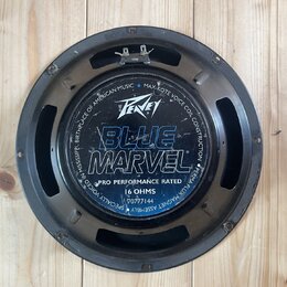 Černý kruhový reproduktor s kovovým rámem. Na středovém krytu je bílé logo Peavey a velký modrý nápis BLUE MARVEL. Dole je uveden text PRO PERFORMANC…