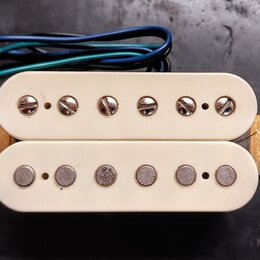 Bílý humbucker s dvěma cívkami a plastovým krytem. Horní cívka má šest kovových šroubů, spodní cívka šest kovových kolíků. Z nástroje vedou modré a z…