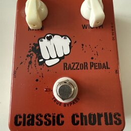 Červený efekt pedál s dvěma bílými otočnými knoflíky. Na horní straně jsou nápisy RATE a WIDTH, uprostřed je logo s bílou pěstí a text RAZZOR PEDAL.…