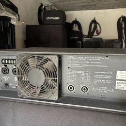 Šedý rackový výkonový zesilovač s kovovým šasi a vestavěným ventilátorem. Na zadním panelu jsou vidět dva konektory SpeakON, napájecí vstup a přepína…