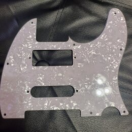 Světle šedý pickguard s perleťovým vzorem pro elektrickou kytaru. Je vyroben z plastového materiálu a obsahuje výřezy pro snímače a ovládací prvky. P…