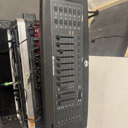 Černý DMX kontrolér s ovládací plochou obsahující posuvníky, tlačítka a displeje. Na přístroji jsou viditelné nápisy DMX OPERATOR a SCENE1, doprováze…