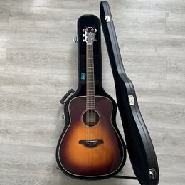 Akustická kytara s tělem typu dreadnought v provedení sunburst (přechod od žluté k tmavě hnědé). Na hlavě nástroje je bílý nápis YAMAHA. Kytara leží…