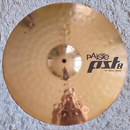 Zlatý kovový činel s povrchem s jemnými kladenými důlky. Na pravé straně je černý nápis pAiste pst8 18" ROCK CRASH. Povrch je v dobrém stavu bez vidi…