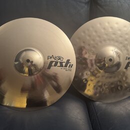 Dvě kovové činely v barvě zlaté. Na levém je nápis pAiste pst8 14" ROCK HATS BOTTOM a na pravém, který má povrch s důlky, nápis pAiste pst8 14" ROCK…
