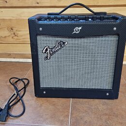 Černý kytarový kombozesilovač s šedou textilní maskou reproduktoru. Na masce je bílý nápis Fender a nad ní se nachází malé kulaté logo. Horní panel o…